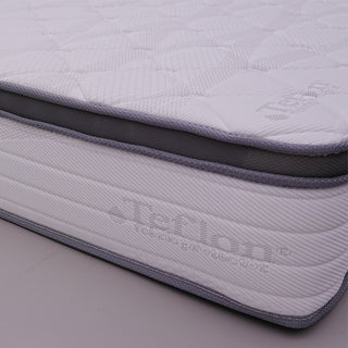 Corner detail of a hotel mattress showing quilted top, grey piping, and fabric protector side panel