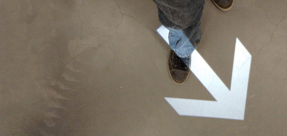 Arrow projected in light onto a concrete floor, a guest stepping across it