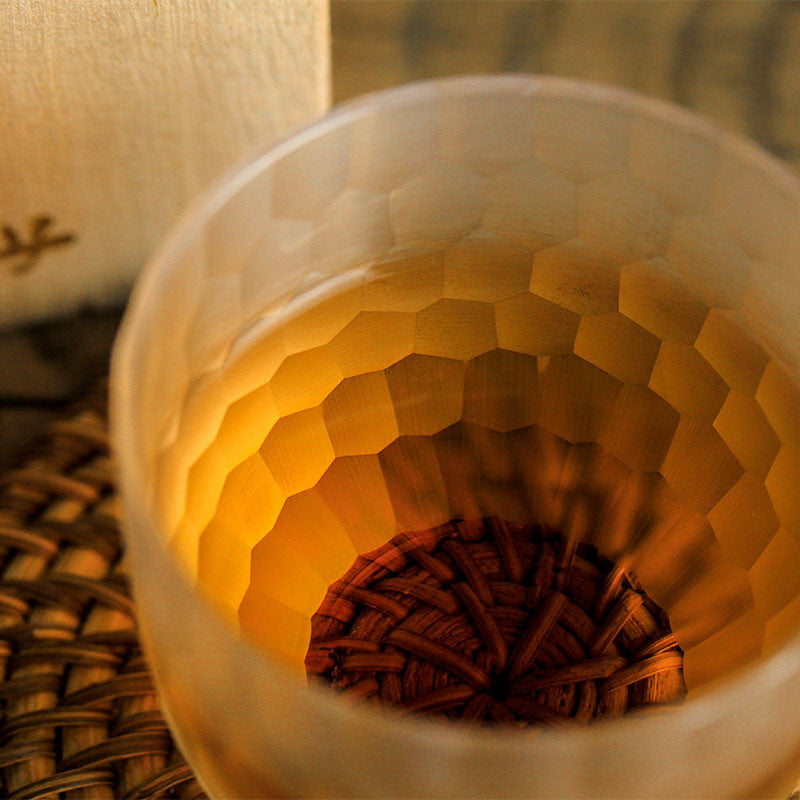 Close-up inside a crystal whiskey glass showing the faceted honeycomb cut pattern lit from below