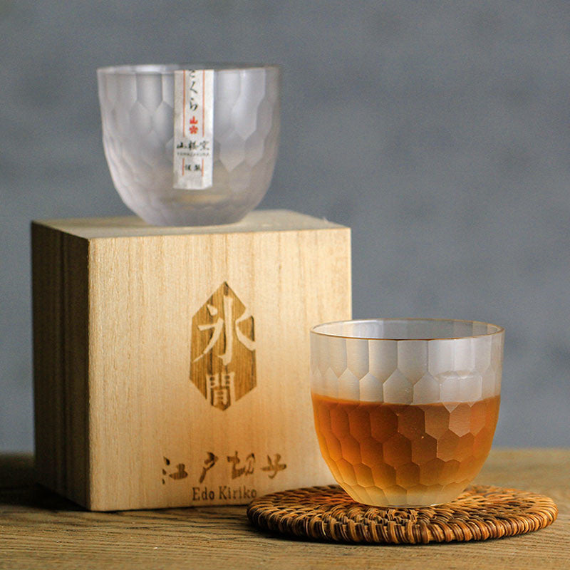 Crystal whiskey glasses with honeycomb cut design, one filled with whisky beside a wooden gift box