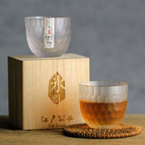 Crystal whiskey glasses with honeycomb cut design, one filled with whisky beside a wooden gift box