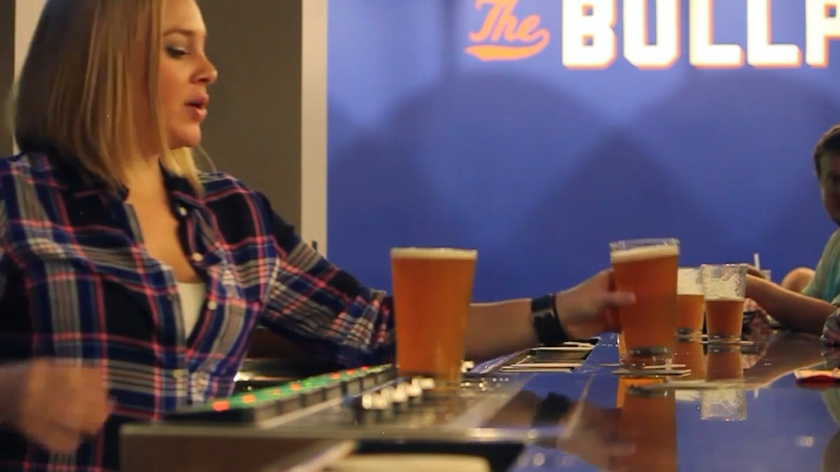 Guest taking a filled pint from the bar while more pints stand on the dispenser pads