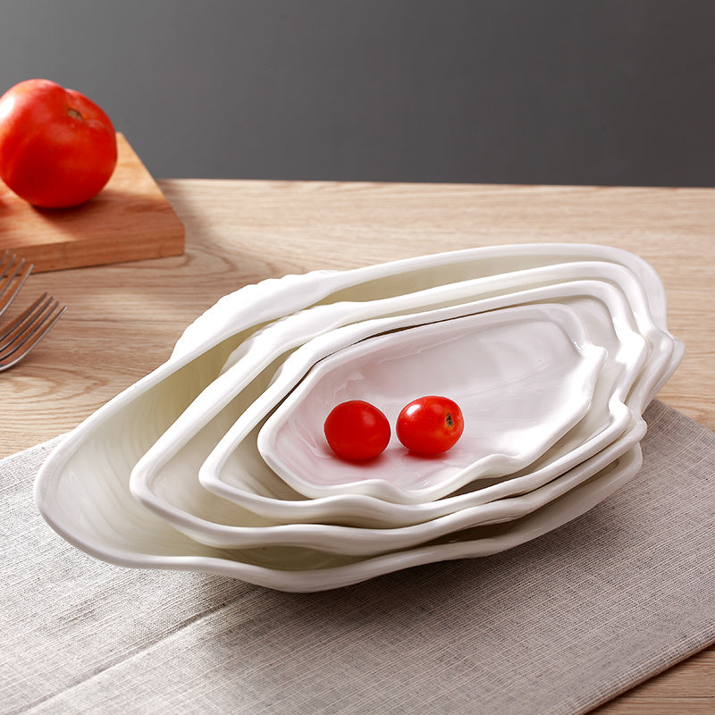 Nested stack of four mother of pearl shell-shaped ceramic plates wholesale, sizes graduating with cherry tomatoes on top