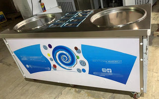 Commercial ice cream machine with two round fry pans, wrapped topping trays and blue swirl front panel on wheels