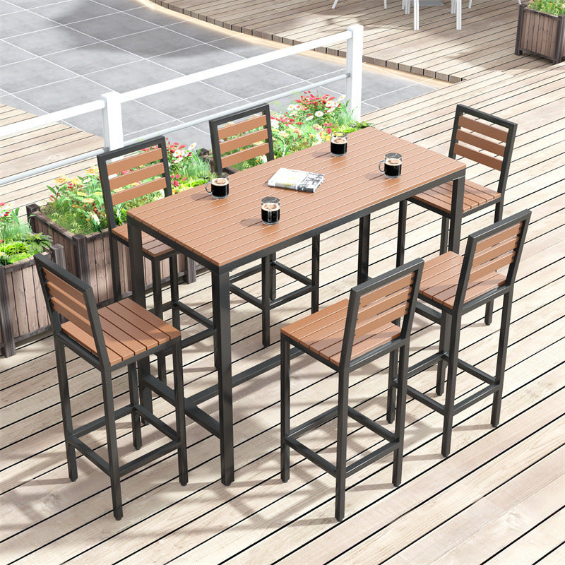 Outdoor bar furniture set with high table and 6 bar stools on a wooden deck patio