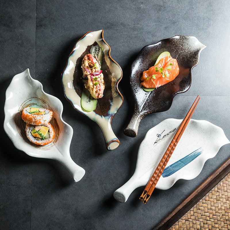 Four leaf-shaped ceramic plates wholesale display styles, holding sushi rolls, salmon, and dishes with chopsticks