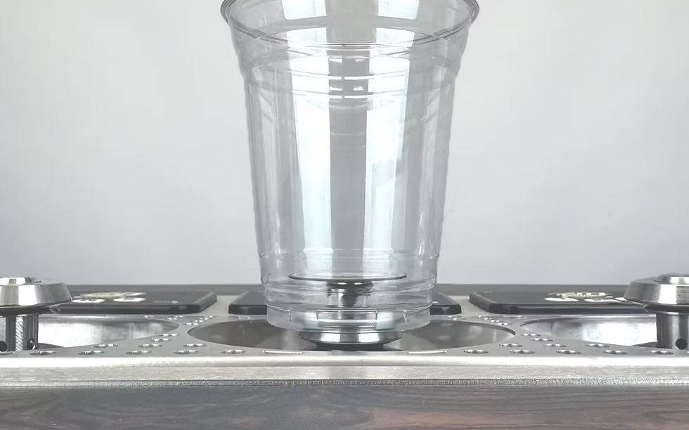 Empty plastic cup seated on the magnetic pad of a four-tap bottoms-up dispenser