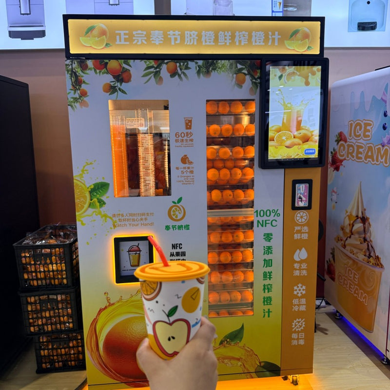 Fresh orange juice vending machine with oranges visible behind the glass