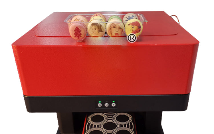 Four printed macarons resting on the lid of the printer above its four-cup tray
