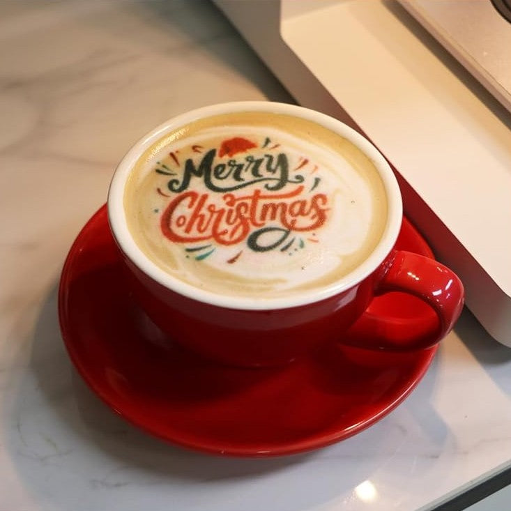 Cup of coffee with an edible design printed across the foam, on a red saucer