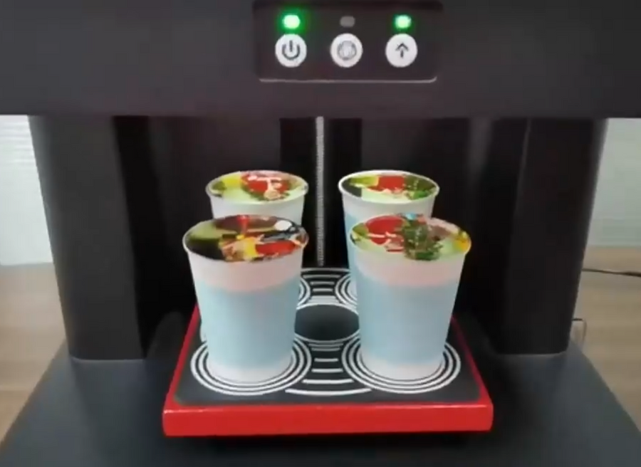 Four printed cups standing on the printer's tray under the machine