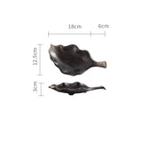 Black leaf-shaped ceramic plate shown from top and side view with measurements 18cm by 12.5cm
