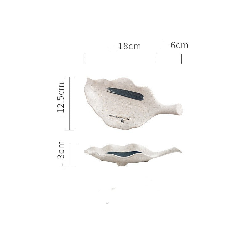 White leaf-shaped ceramic plate with blue brushstroke design shown from top and side with measurements
