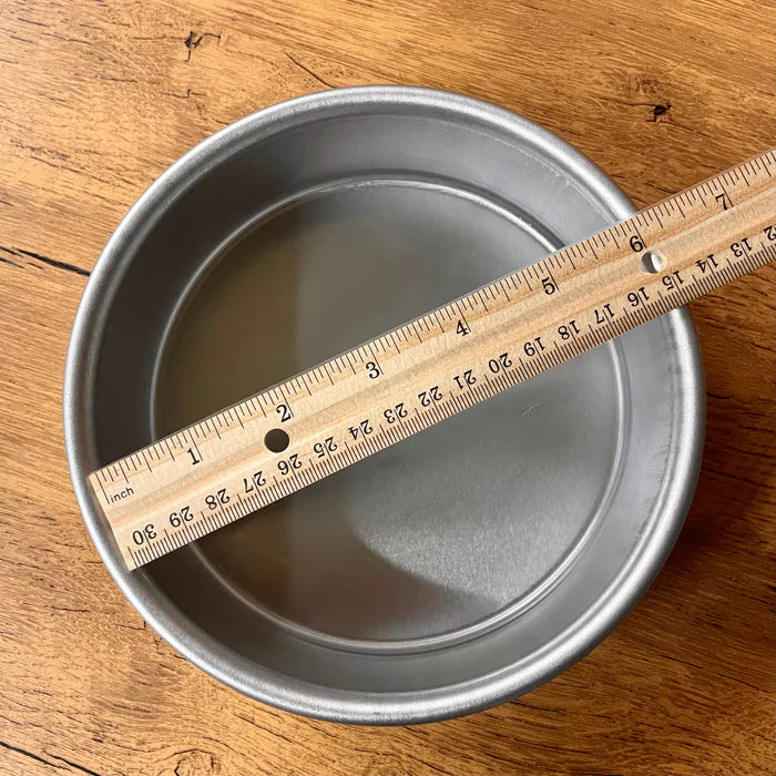 A ruler laid across a round cake pan to measure the printable area