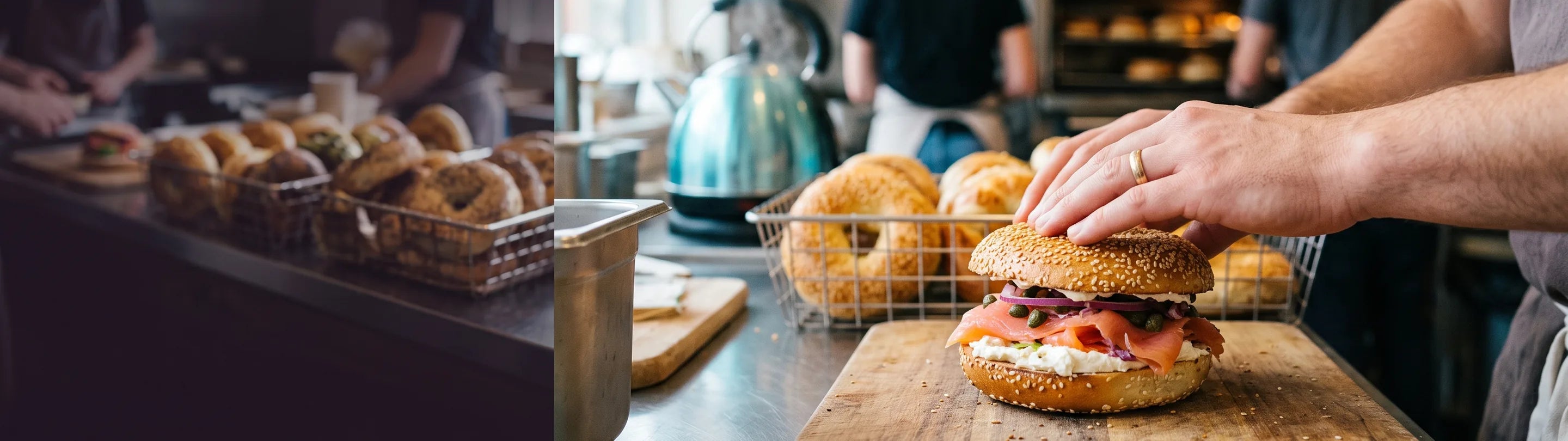 A sesame bagel filled with cured salmon, cream cheese, capers and red onion on a wooden board, a wire basket of bagels and a steel kettle behind it