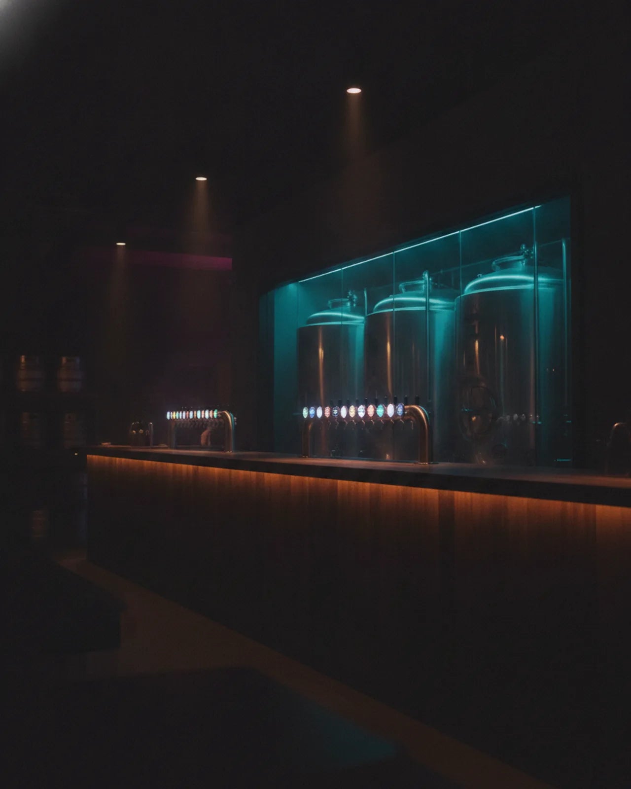 The tap row seen from the guest side of the bar, conditioning tanks rising behind it