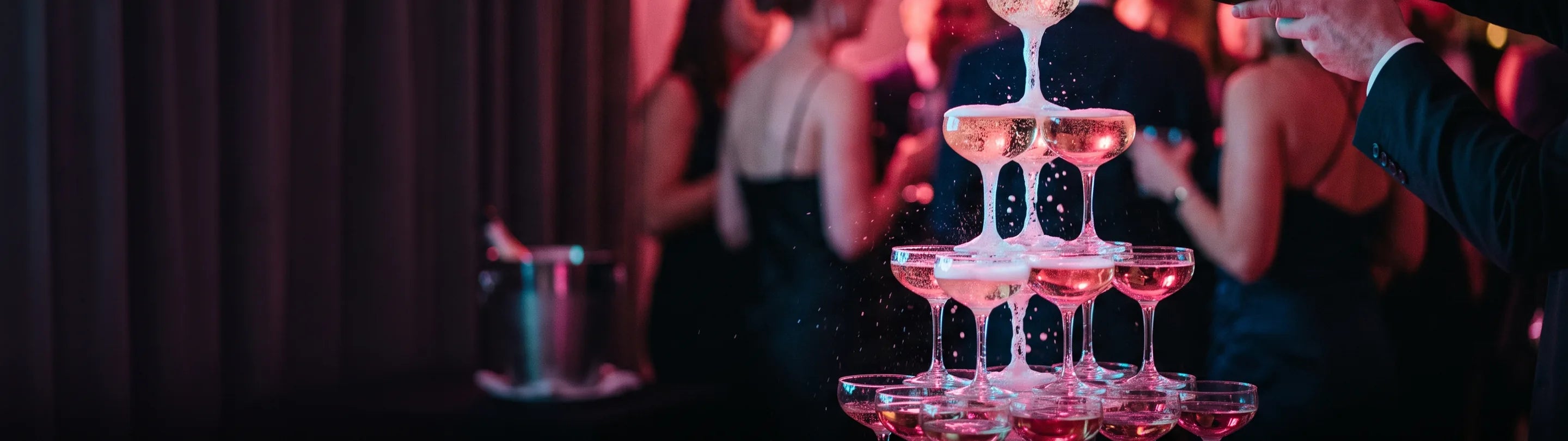 Champagne poured into a flute at a bar counter, ice bucket and bottles in the background
