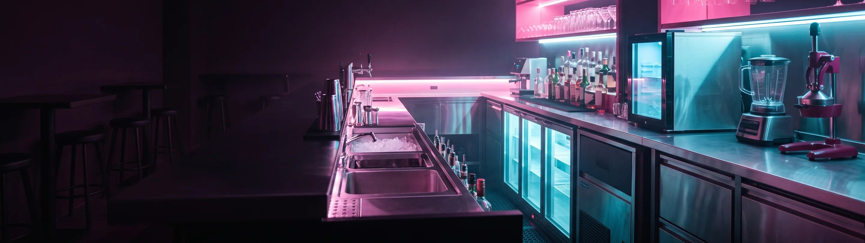 Bar counter under warm light with glassware, taps and a barista station in the background